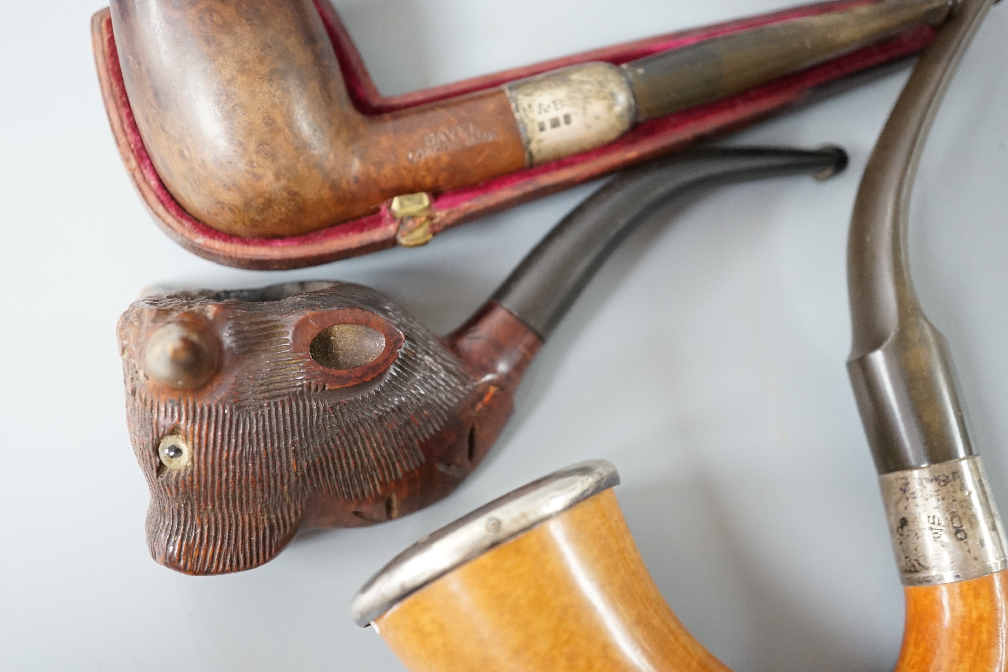 A cased Savel burr wood smokers pipe with silver collar, another pipe with silver collar and rim together with a novelty carved wood and horn ‘cow’ pipe